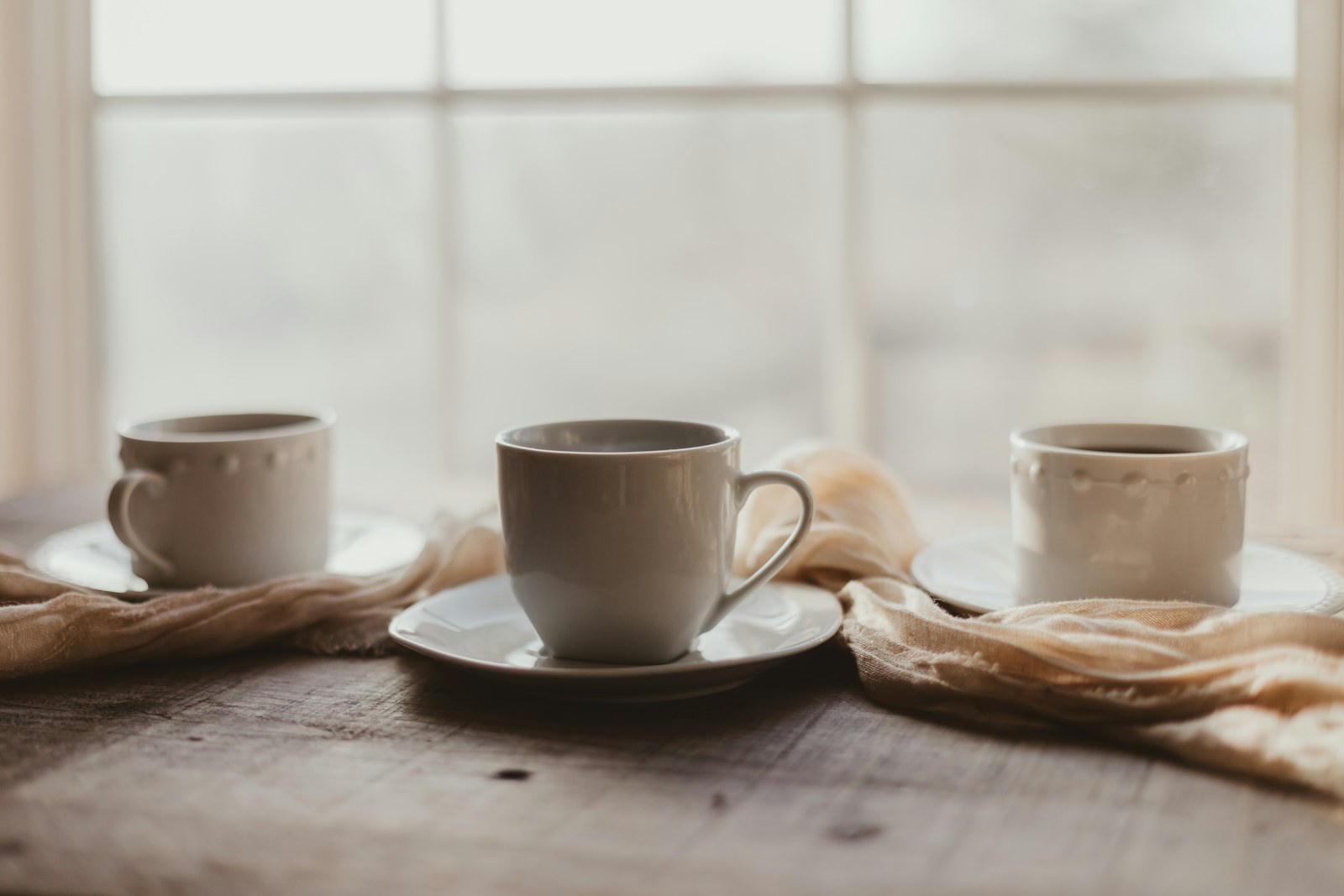 Cups of coffee on a wooden table by a window
